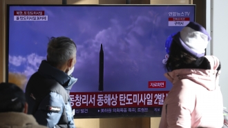 People watch a TV screen showing a news program about North Korea's missile launch.