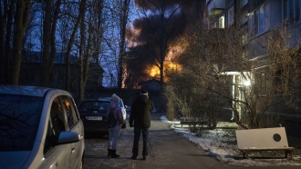 Residents watch a burning building after a Russian drone strike.