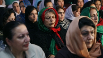An Afghan woman, center, wears an Afghan flag as a head scarf during a gathering.