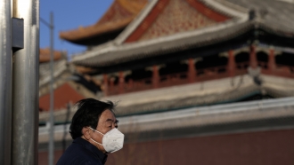 A resident wears a mask as he stands near the Lama Temple in Beijing