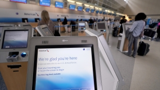 Travelers use a kiosk to check bags at the airport.