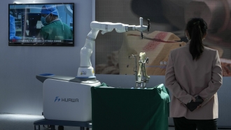 A woman watches a video showing a robotic arm performs bone surgery