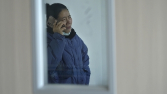A relative of injured people reacts as she talks to a phone at a hospital following a traffic accident.