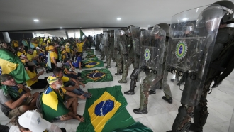 Supporters of Brazil's former President Jair Bolsonaro, sit in front of police inside Planalto Palace after storming it.