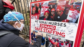 A nurse signs a board demanding safe staffing at a rally.