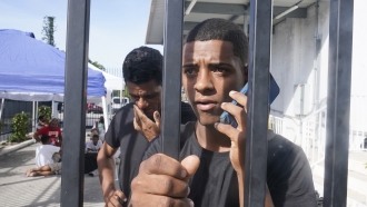 A young man from Cuba is on a phone call at a U.S. Customs and Border Protection facility