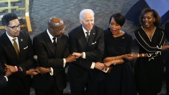 President Joe Biden, center, holds hands with Sen. Raphael Warnock, second from left, and former Mayor Keisha Lance Bottoms.