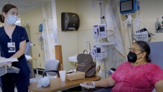 A nurse checks on Carol Turner as she receives an IV during a clinic trial