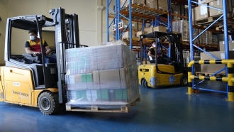 Forklift drivers transporting pallets of product.