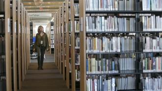 A person walks past shelves of books in a library.