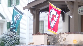 A Philadelphia Eagles flag and a Kansas City Chiefs flag fly next to each other on a porch.