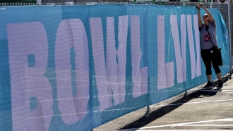 Eilish GrayWoulfe covers a fence with graphics outside State Farm Stadium