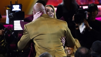 Adele, back, and Dwayne "The Rock" Johnson embrace at the 65th annual Grammy Awards.