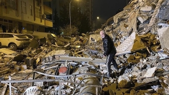A man searches collapsed buildings in Turkey.