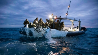 Members of the U.S. Navy pull a suspected Chinese spy ballon from the ocean.