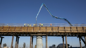 workers pour concrete on to one of the elevated sections of the high-speed rail that will cross over the San Joaquin River