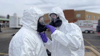 Ohio National Guard members in hazmat suits prepare to assess hazards from a train derailment.