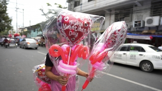 A man carries heart-shaped balloons at a flower market