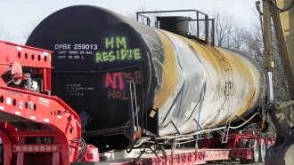 A tank car sits on a trailer as the cleanup of portions of a Norfolk Southern freight train that derailed continues.