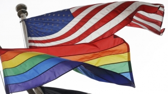 The Rainbow Flag, an international symbol of LGBT liberation and pride, flies beneath the American flag