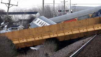 Multiple cars of a Norfolk Southern train lie toppled on one another after derailing at a train crossing in Ohio.