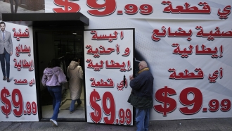 Store displays advertising in Arabic that reads "Italian clothes and shoes for 9.99 $" in Beirut, Lebanon.