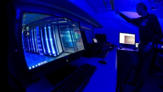 A man stands in front of screens at a cybercrime center.