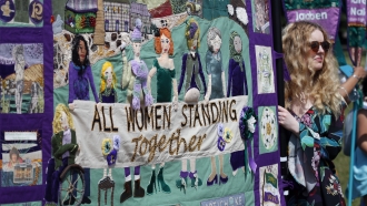 Participants march through the streets with "all women standing together" banner.