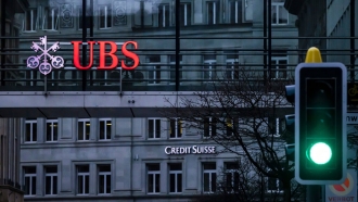 A traffic light signals green in front of the logos of the Swiss banks Credit Suisse and UBS in Zurich, Switzerland