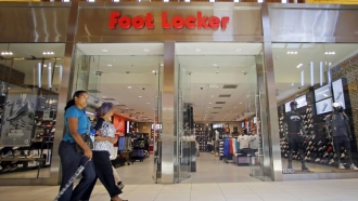Patrons walk in front of a Foot Locker store inside of a mall