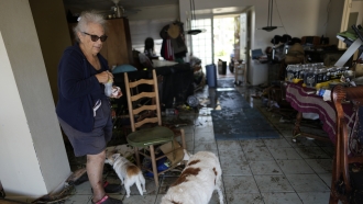 Judy Wolff stands in her damaged riverfront home in Fort Myers, Fla.