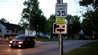 A car drives past a speed limit sign.