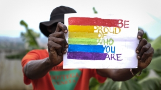 A gay Ugandan man holds a pride sign