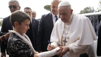 Pope Francis autographs the plaster cast of a child as he leaves the Agostino Gemelli University Hospital in Rome