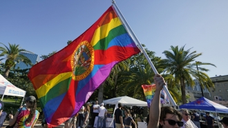 A protester waving a pride flag with the Florida State Seal.