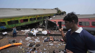 People inspect the site of passenger trains that derailed in India
