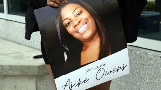 A person holds a "Justice for Ajike Owens" poster