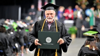 72-year-old holds up his diploma after graduating from Georgia Gwinnett College
