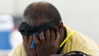 Man wipes sweat from his face inside a cooling center.