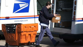 A U.S. Postal Service employee works outside a post office.