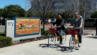 Two people ride bikes outside Google offices in California
