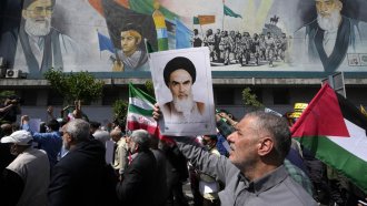 Iranian worshippers walk past a mural showing the late revolutionary founder Ayatollah Khomeini.