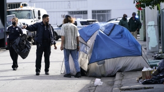 A police officer talks with a homeless person, prior to a cleaning of the street