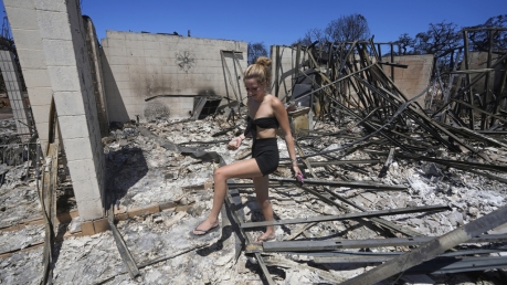 Sydney Carney walks through her home that was destroyed by a wildfire.