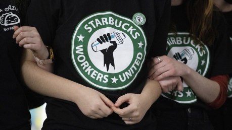 Starbucks employees and supporters link arms during a union election watch party