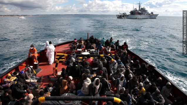 Rescued refugees and migrants wait to disembark from the Italian Navy Ship "Spica" onto a tugboat that will take them to the harbor of Pozzallo.