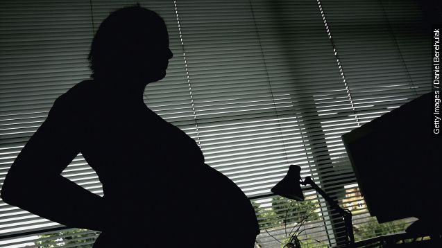 In this photo illustration a pregnant woman is seen stood at the office work station.