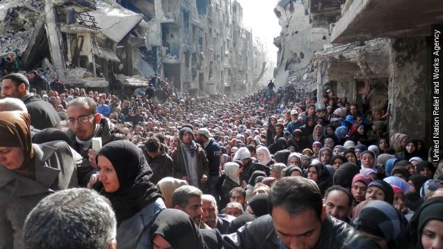 Residents wait in line to receive food aid distributed in the Yarmouk refugee camp on January 31, 2014 in Damascus, Syria.