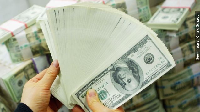 A hand displays a stack of $100 bills.