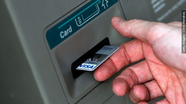 A man puts a card into an ATM.